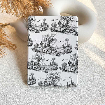 A black Kindle case with a vintage Halloween pattern featuring skulls and trees, displayed on a white background with a decorative vase in the background.