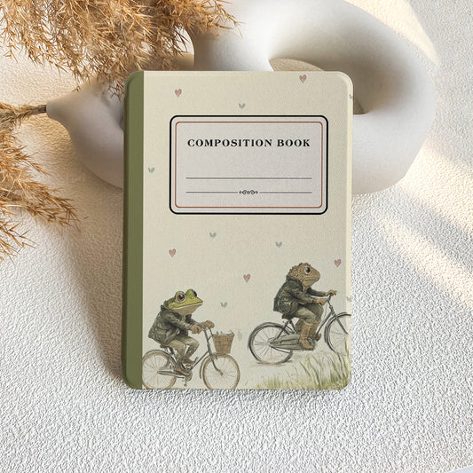 Composition book with frog illustration on a textured surface