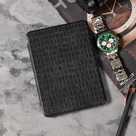 Black textured wallet with a Hublot watch on a textured surface
