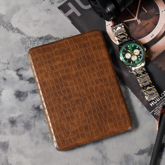Brown textured wallet and green watch on a gray surface with 'Hugo' branding.