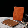 Two brown crocodile-patterned leather cases on a gray surface with a black background