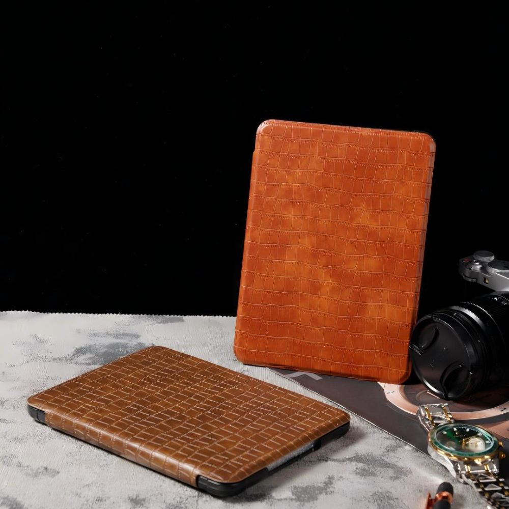Two brown crocodile-patterned leather cases on a gray surface with a black background
