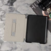 Two tablet cases, one beige and one black, on a marble surface with a camera lens and strap.