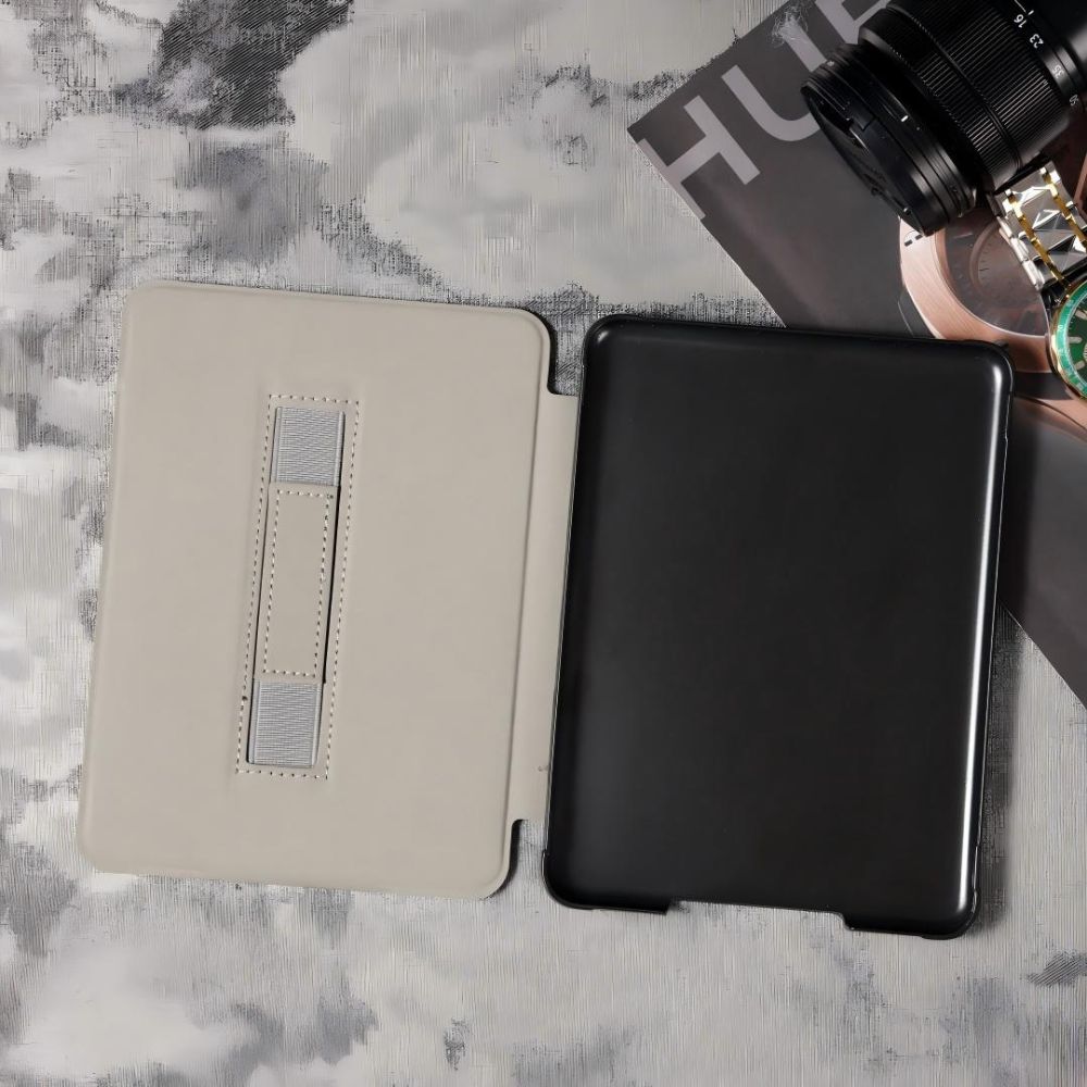 Two tablet cases, one beige and one black, on a marble surface with a camera lens and strap.
