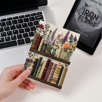 Decorative bookend with floral and book design on a desk with laptop and tablet.