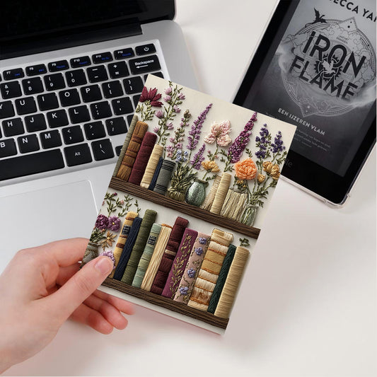 Decorative bookend with floral and book design on a desk with laptop and tablet.