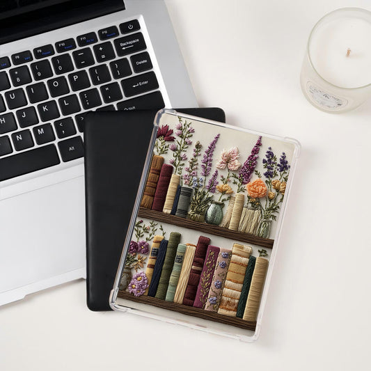 kindle case with floral and book design on a desk next to a laptop