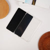 Black notebook with a clear cover on a white surface with woven coasters.