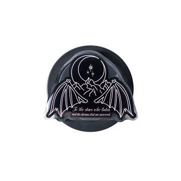 Black and white decorative item with bat wings and celestial design on a light gray background