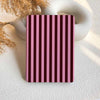 Rectangular object with pink and purple vertical stripes on a textured surface.