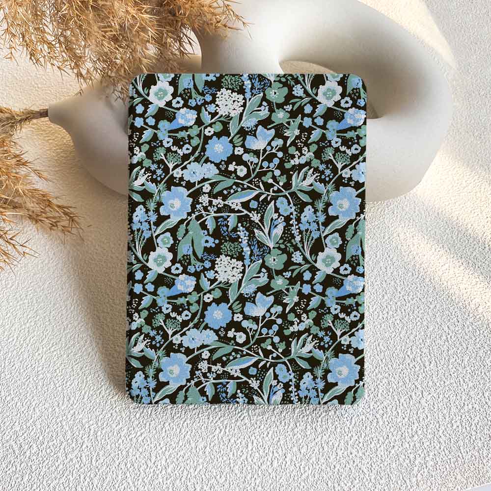 Floral patterned notebook on a textured surface with dried plants.