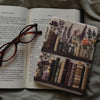 Decorative book with embroidered cover featuring plants and books, placed on an open book.